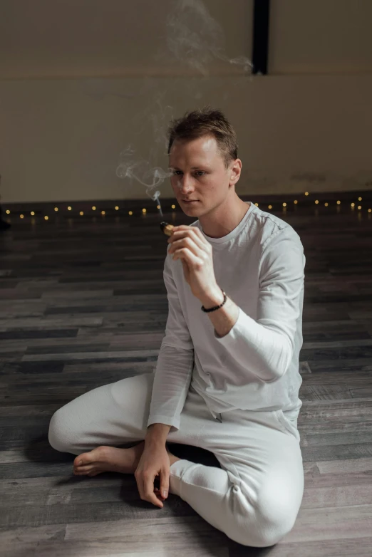 a woman sitting on the floor smoking a cigarette, kundalini energy, photo of a man, lachlan bailey, low quality photo