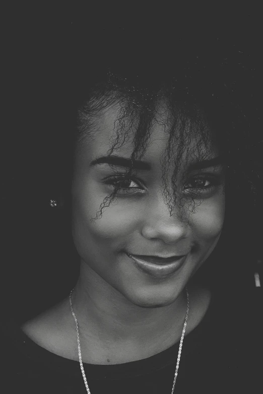 a black and white photo of a woman smiling, a black and white photo, pexels contest winner, black teenage girl, avatar image, grainy photorealistic, 2 4 year old female model