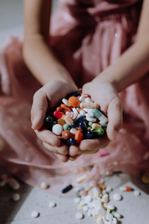 a woman in a pink dress holding a handful of pills, a picture, by Julia Pishtar, pexels, made of multicolored crystals, cute girls, multiple stories, made of candy