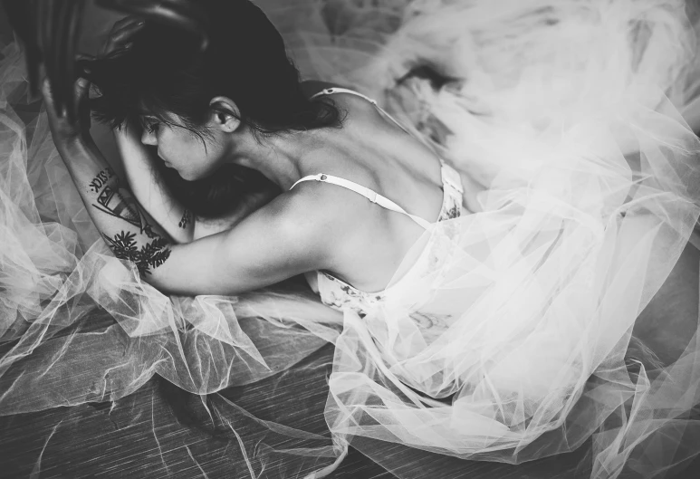 a black and white photo of a woman in a dress, tumblr, romanticism, laying down, tulle and lace, upset, brandon woelfel