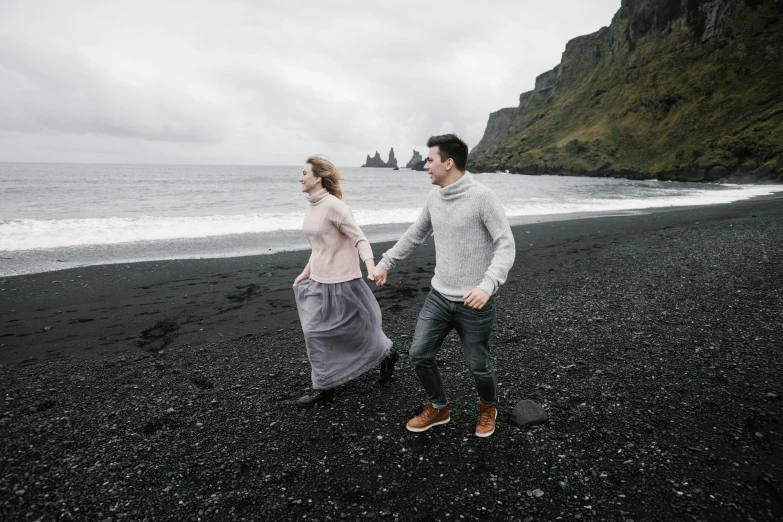 a man and woman walking on a black sand beach, by Hallsteinn Sigurðsson, pexels contest winner, renaissance, casually dressed, promotional image, grey, royal photo