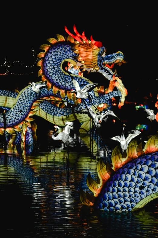 a dragon statue floating on top of a body of water, during the night