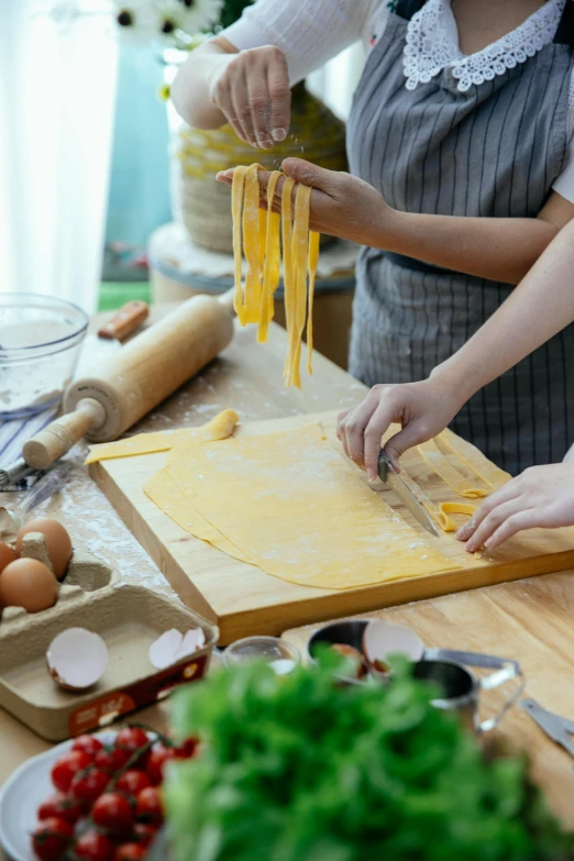 a group of people preparing food in a kitchen, intricate pasta waves, promotional image, wooden, square