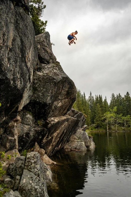 a person jumping off a cliff into a lake, by Sven Erixson, boreal forest, rock climbing, shot with sony alpha, boys