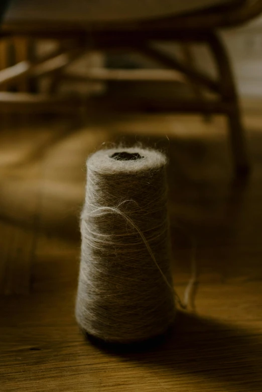 a spool of yarn sitting on top of a wooden floor, unsplash, arts and crafts movement, alessio albi, sheep wool, low-light photograph, woven with electricity