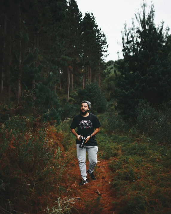 a man standing in the middle of a forest, a polaroid photo, pexels contest winner, wearing a t-shirt, non-binary, walking at the garden, lush vista