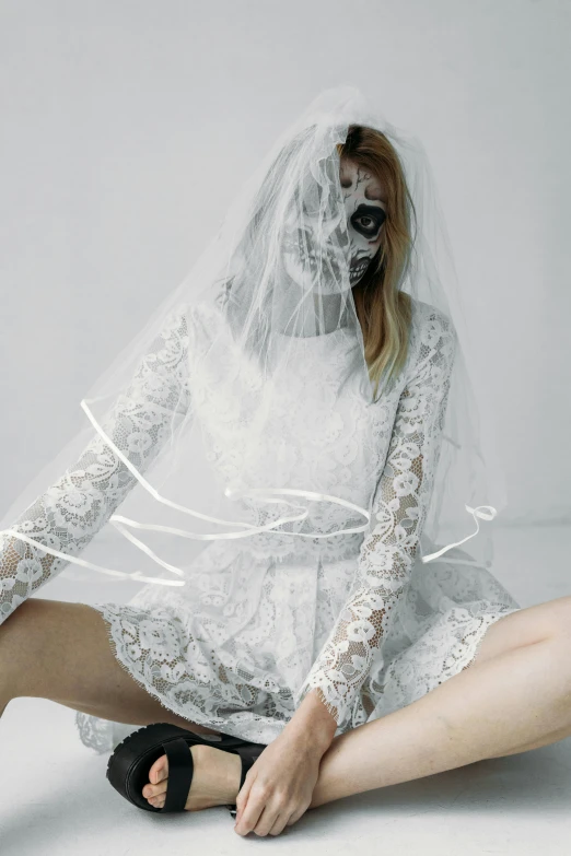 a woman sitting on the ground with a veil over her head, an album cover, inspired by Elsa Bleda, white lace clothing, showstudio, robot ghost mask, wedding dress