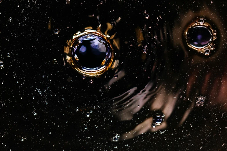 a couple of rings floating on top of a body of water, an album cover, pexels contest winner, space art, made of ferrofluid, space station light reflections, bubbles, wet reflections in square eyes