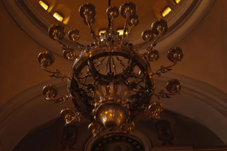 a chandelier hanging from the ceiling of a building, by Attila Meszlenyi, unsplash, baroque, in a church. medium shot, cinematic lights hyperdetailed, brown, brass plated