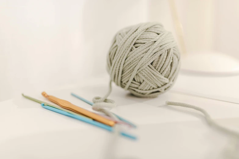 a ball of yarn sitting on top of a table, light grey, modelling clay, miscellaneous objects, instrument