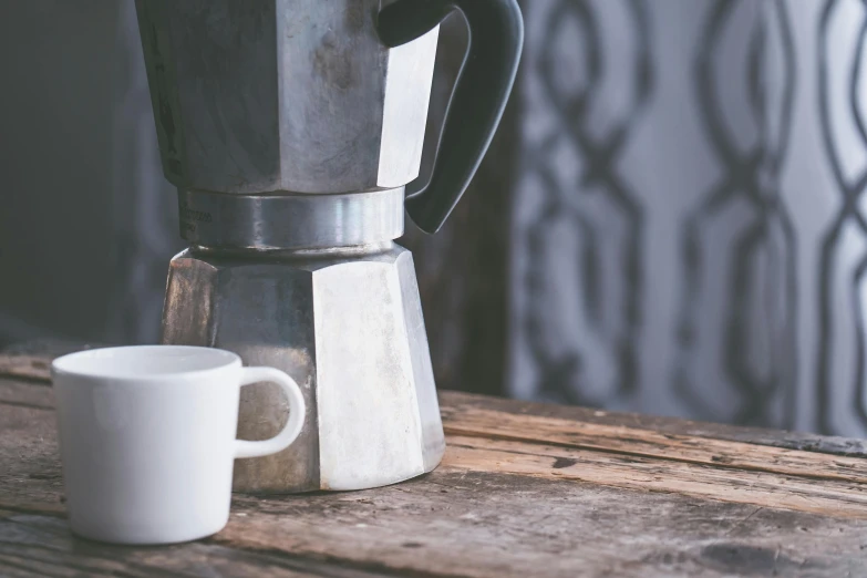 a coffee pot sitting on top of a wooden table next to a cup, pexels contest winner, private press, grey, caucasian, very pale, thumbnail