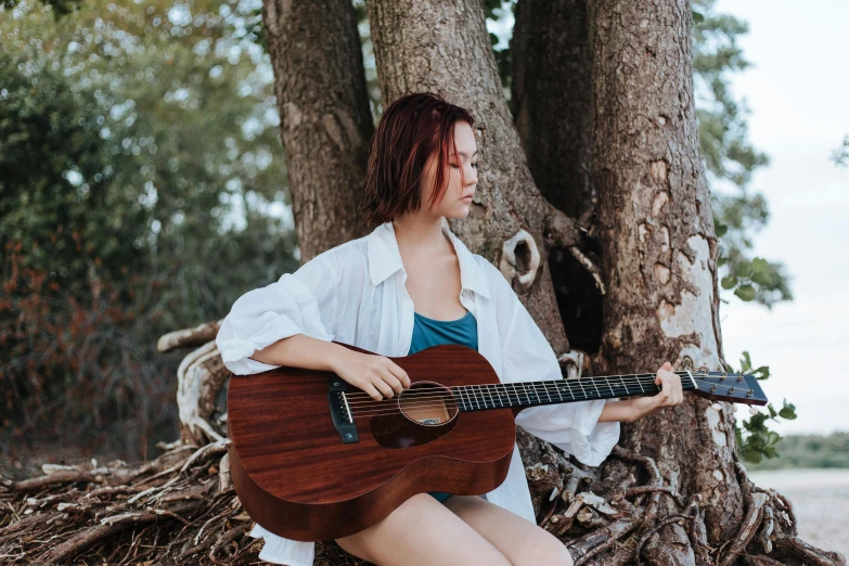 a woman sitting next to a tree with a guitar, pexels contest winner, 🦩🪐🐞👩🏻🦳, nanae kawahara, cardboard, white sleeves