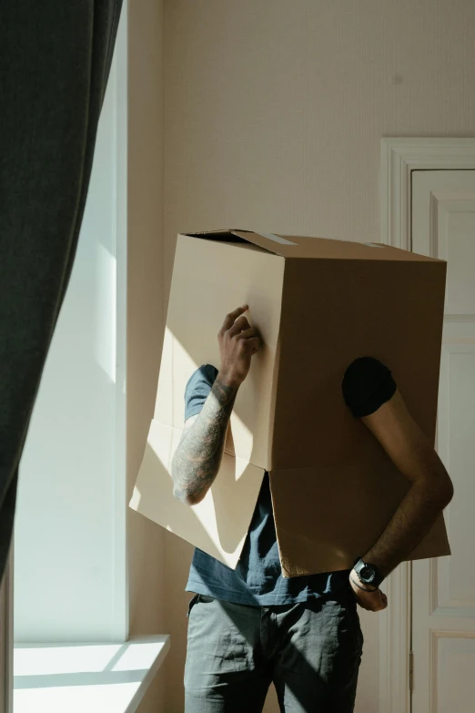 a man with a cardboard box on his head, pexels contest winner, minimalism, backlight body, square face, an intruder, ignant