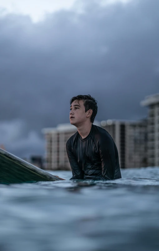 a man sitting on top of a surfboard in the ocean, profile image, cinematic movie image, looking serious, darren quach