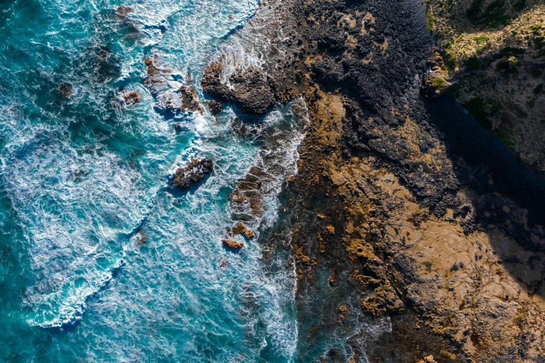 a large body of water next to a cliff, pexels contest winner, process art, close-up from above, oceanside, te pae, rocky roads