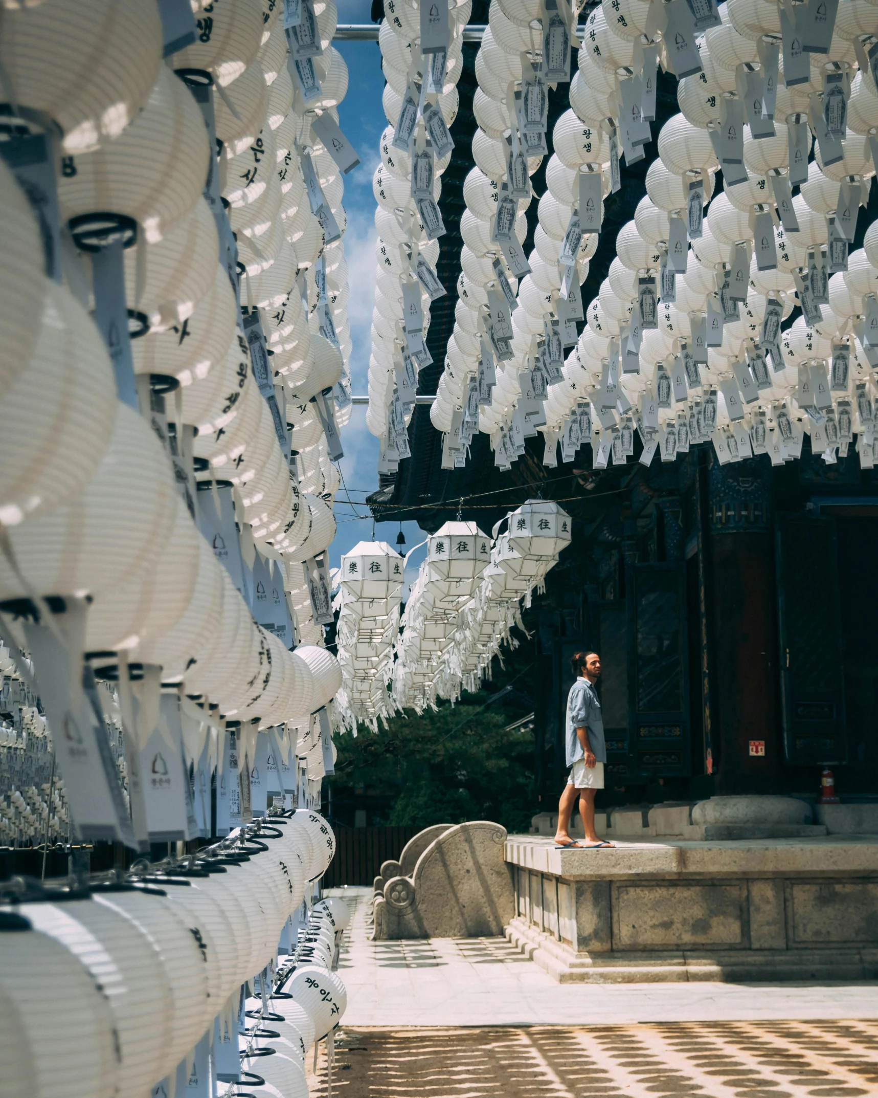 a man that is standing in front of a building, by Kim Tschang Yeul, unsplash contest winner, interactive art, with paper lanterns, lots of white cotton, inside her temple, okinawa japan