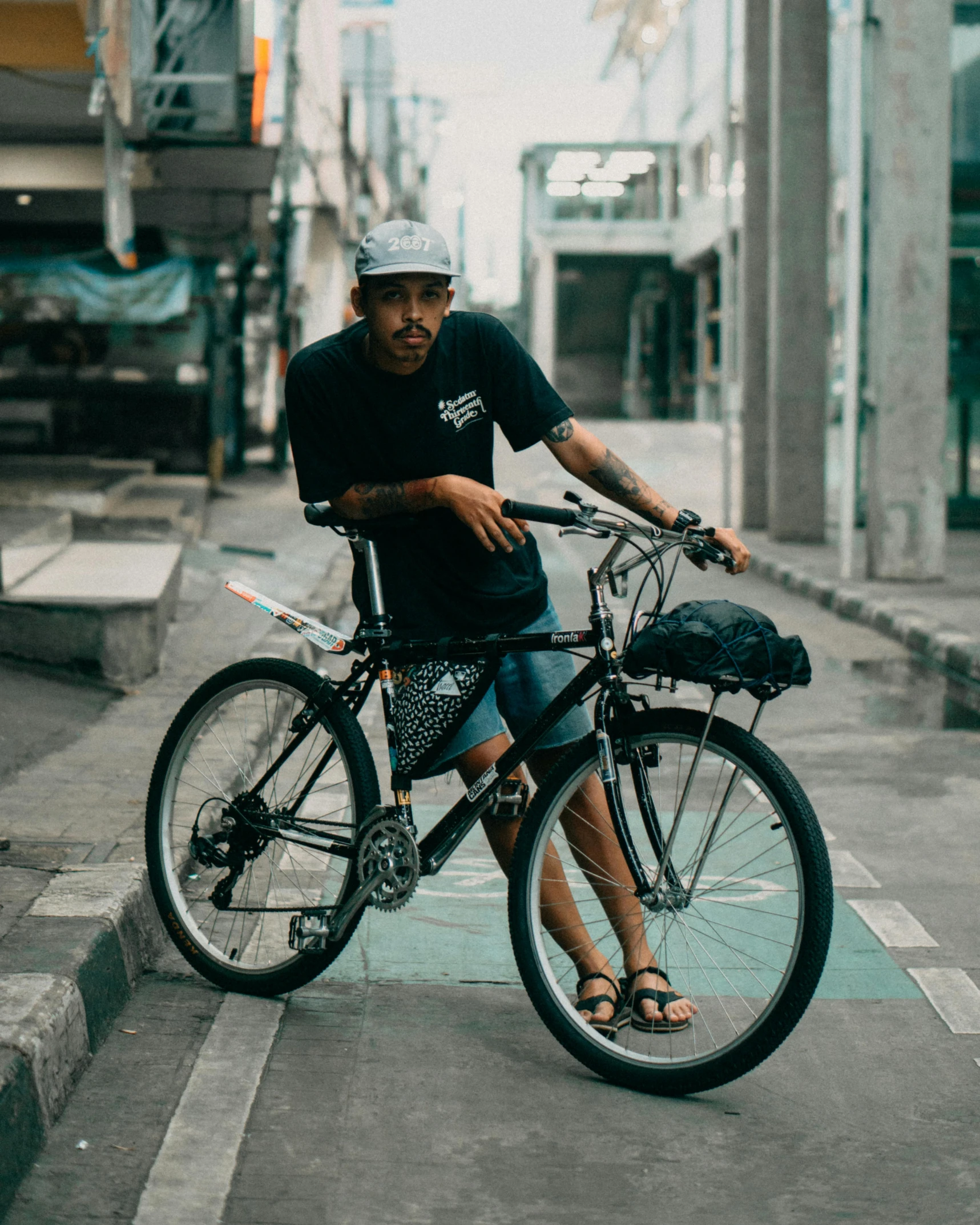 a man riding a bike down a city street, pexels contest winner, realism, baggy clothing and hat, wearing shorts and t shirt, with a roof rack, thawan duchanee