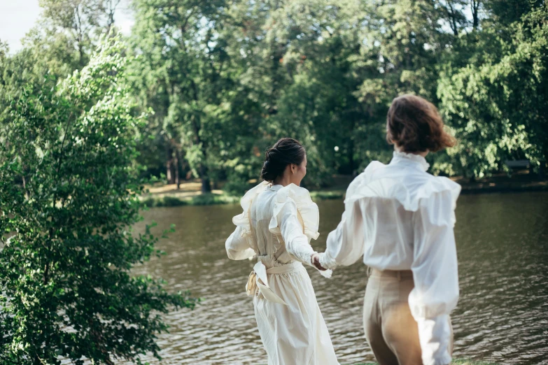 a couple of women standing next to a body of water, by Emma Andijewska, unsplash, renaissance, wearing white silk, walking at the park, wearing a linen shirt, 15081959 21121991 01012000 4k