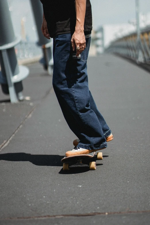 a man riding a skateboard down a sidewalk, by Niko Henrichon, unsplash, renaissance, large pants, wearing denim, caramel. rugged, 40 years old women