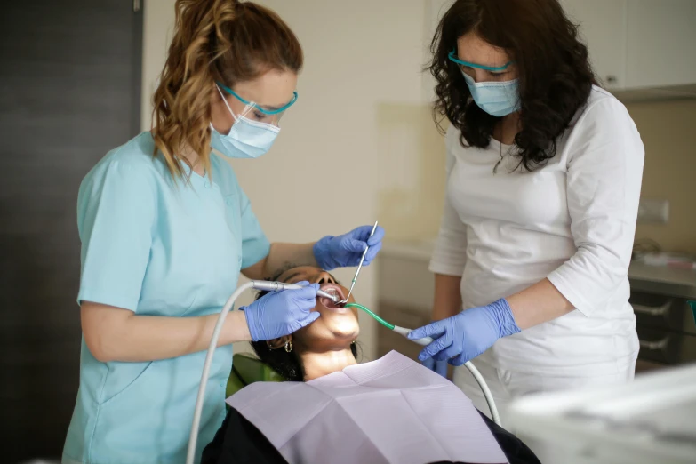 a woman getting her teeth examined by a dentist, by Adam Marczyński, pexels contest winner, hurufiyya, surgical gown and scrubs on, thumbnail, small jaw, group photo