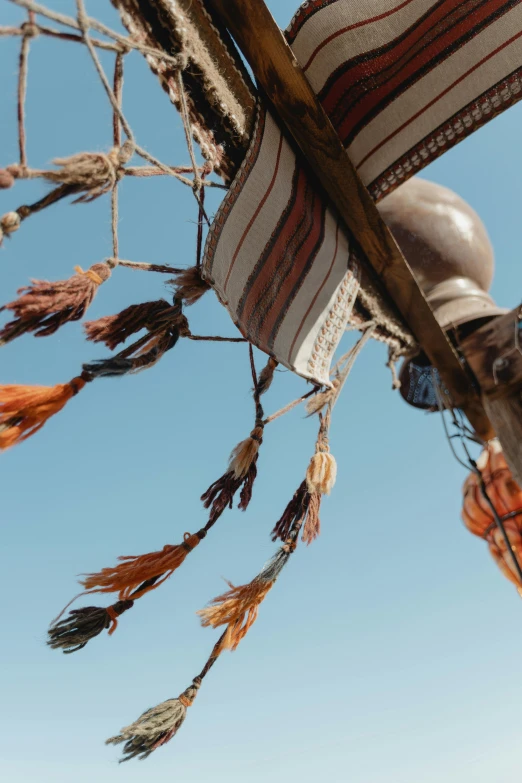 a close up of a piece of cloth on a pole, an abstract sculpture, hurufiyya, on a pirate ship, feathers growing from arms, overhanging branches, slide show