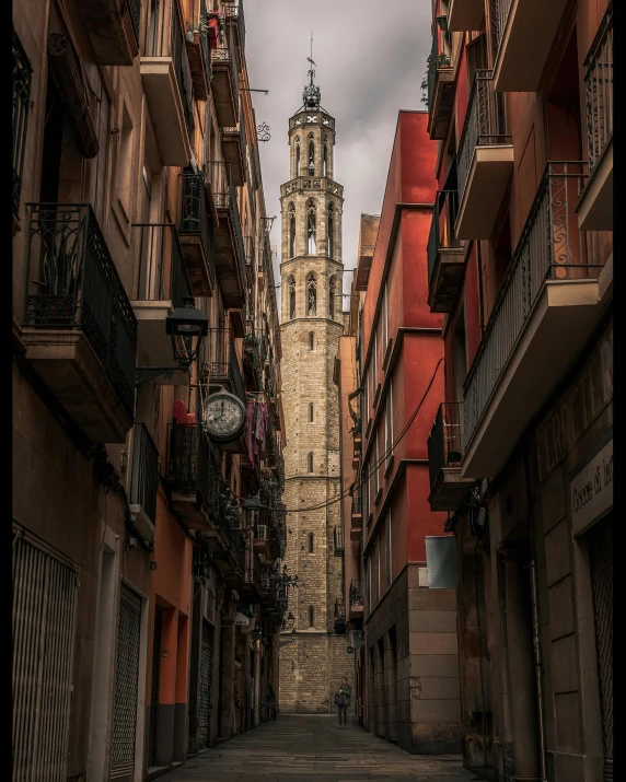 a narrow street with a clock tower in the background, inspired by Modest Urgell, pexels contest winner, romanesque, grey, tall skyscraper, color image, full of light