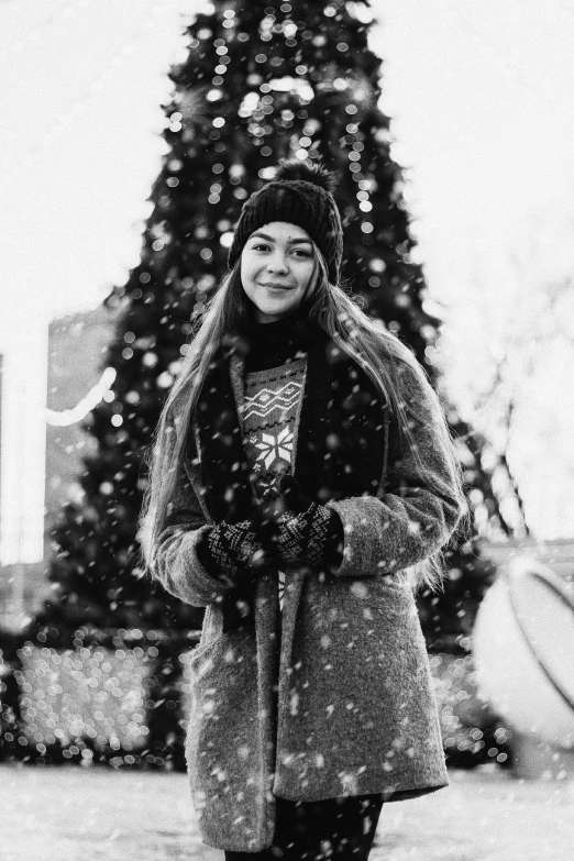 a woman standing in front of a christmas tree, a black and white photo, by Felix-Kelly, pexels contest winner, realism, snow fall, 🤤 girl portrait, happy girl, dasha taran