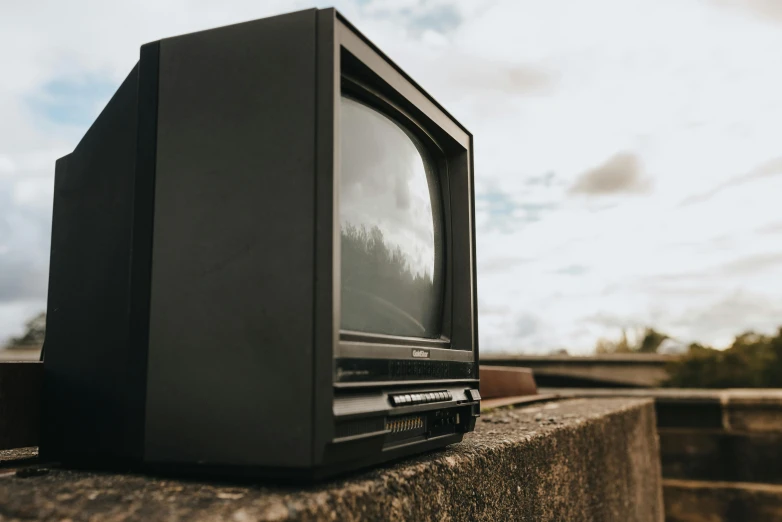 a small television sitting on top of a cement wall, unsplash, video art, crt tubes, politics, black, 15081959 21121991 01012000 4k