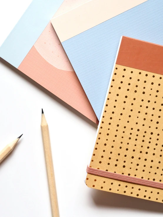 a notebook sitting on top of a table next to a pencil, peach and goma style, thumbnail, modern pastel colours, polka dot