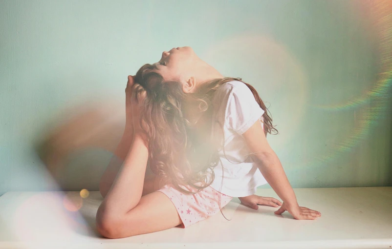 a woman sitting on top of a white counter, inspired by Elsa Bleda, unsplash, light and space, little girl with magical powers, upside down, girl with brown hair, pastel faded effect