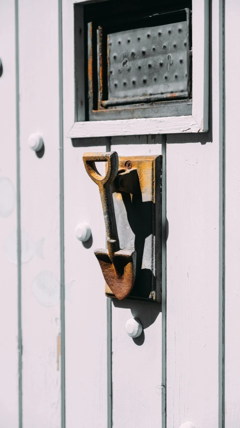 a close up of a metal object on a wall, inspired by Clarice Beckett, unsplash, spanners, small path up to door, seaside, wooden