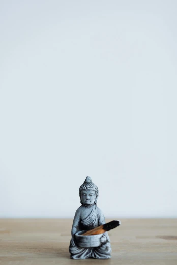 a small statue sitting on top of a wooden table, unsplash, minimalism, hinduism, blue and grey, toy photo, dwell