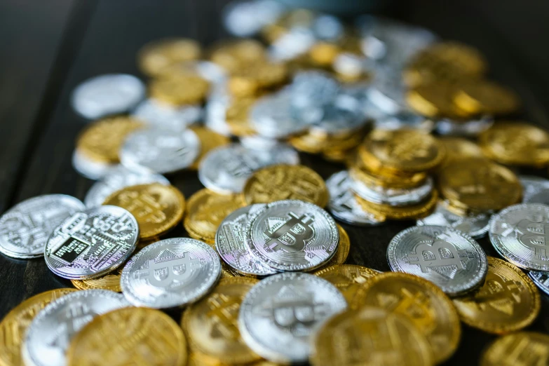 a pile of coins sitting on top of a wooden table, draped in shiny gold and silver, avatar image, 1 petapixel image, bitcoin