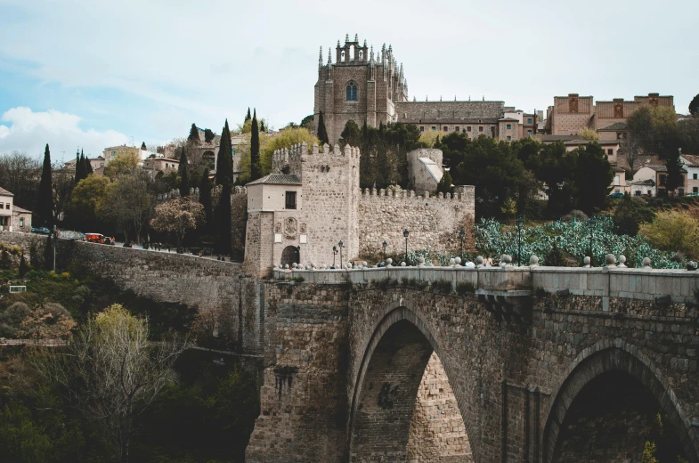 a bridge over a river with a castle in the background, inspired by Modest Urgell, pexels contest winner, city on a hillside, spanish princess, thumbnail, built into trees and stone