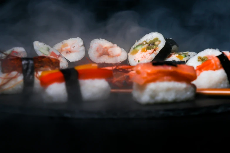 a close up of a plate of sushi on a grill, a still life, by Niko Henrichon, trending on unsplash, mingei, dark and misty, avatar image