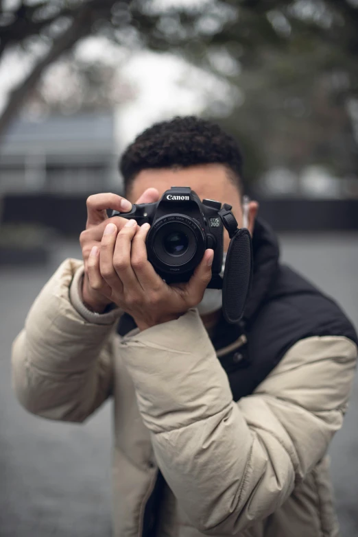 a man taking a picture with a camera, posing for the camera, looking down on the camera