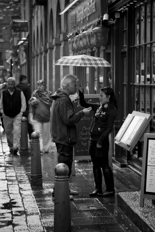 a group of people walking down a street holding umbrellas, a black and white photo, pexels contest winner, stood outside a corner shop, glasgow, dark people discussing, (beautiful) girl