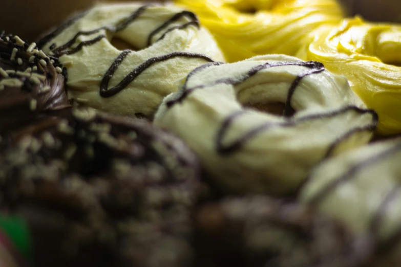 a box filled with lots of different kinds of donuts, a portrait, pexels, hurufiyya, black and yellow, macro details, swirl, thumbnail