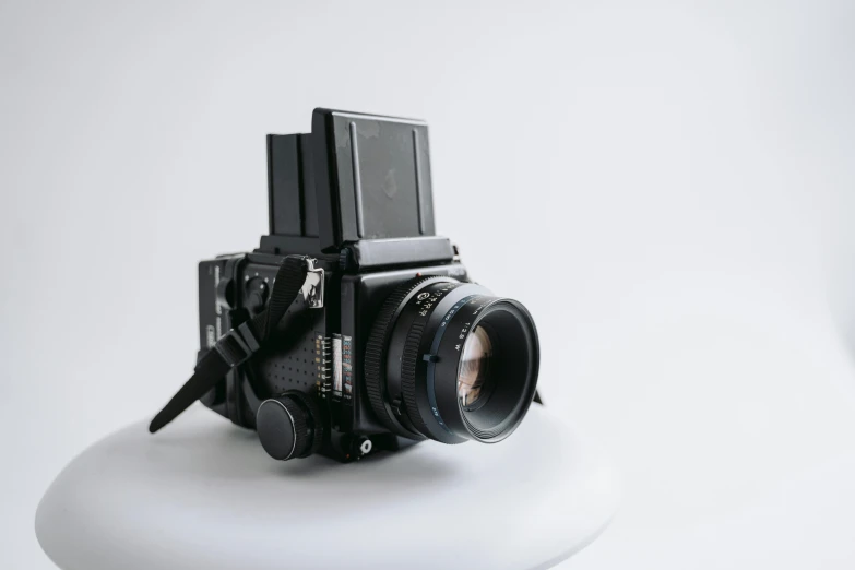 a black camera sitting on top of a white table, by Will Ellis, unsplash, photorealism, mamiya rb 6 7, on a pale background, super panavision 70, front profile shot