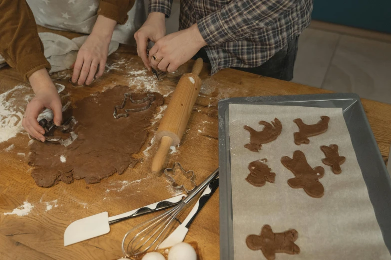 a couple of people that are making cookies on a table, inspired by Sarah Lucas, trending on pexels, folk art, cut out, brown, seasonal, 15081959 21121991 01012000 4k