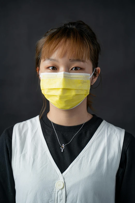 a woman wearing a face mask against a black background, inspired by Ye Xin, healthcare worker, yellow, teenage girl, 奈良美智