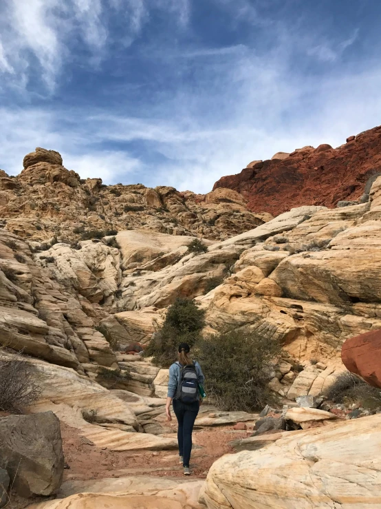 a person with a backpack walking through a rocky area, in las vegas, ((rocks)), emily rajtkowski, scarlett hooft