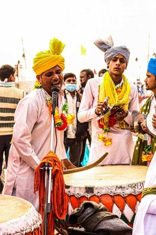 a group of men standing around a drum, pexels contest winner, samikshavad, with yellow cloths, wearing a turban, square, banner