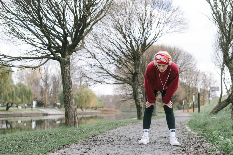 a person standing on a path with trees in the background, by Julia Pishtar, pexels contest winner, happening, wearing a track suit, working out, wearing a red gilet, upset