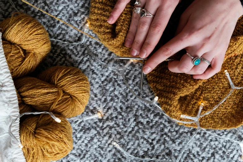 a close up of a person knitting a ball of yarn, by Julia Pishtar, firefly lights, high angle close up shot, ochre, promo image