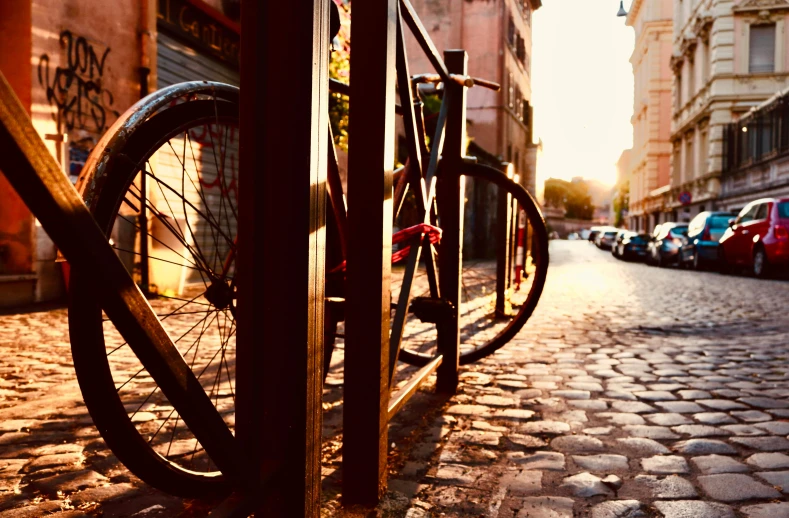 a bicycle chained to a fence on a cobblestone street, pexels contest winner, golden hour scene, streets of heidelberg, work of art, sunflare