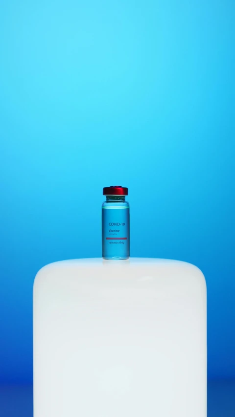 a bottle of water sitting on top of a table, inspired by Évariste Vital Luminais, conceptual art, blue colors with red accents, healthcare, mit technology review, vibrant vials