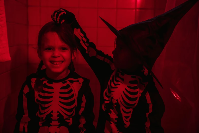 two little girls dressed up in halloween costumes, by Emma Andijewska, pexels, symbolism, red neon, bones, still from stranger things, creepy backrooms