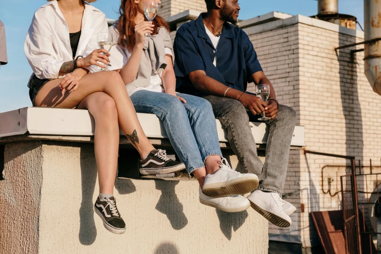 a group of people sitting on top of a building, by Carey Morris, trending on pexels, high soles, drinking, wearing white sneakers, flirting