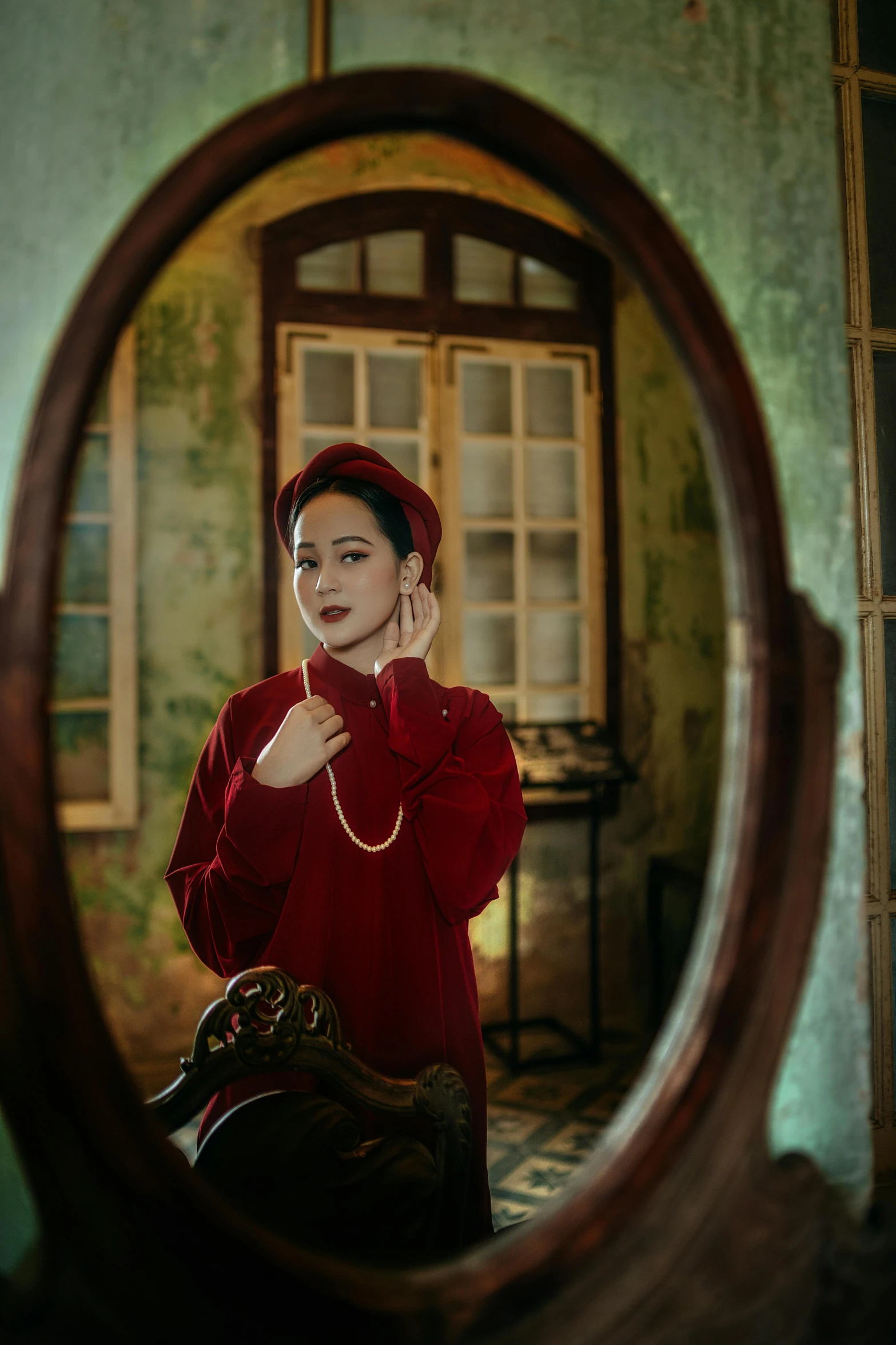 a woman taking a picture of herself in a mirror, a portrait, inspired by Elsa Bleda, pexels contest winner, ao dai, wearing a red captain's uniform, vintage old, ( ( theatrical ) )